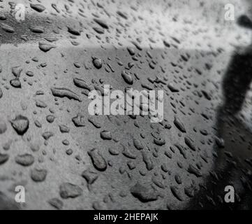 Water droplets on a dark grey metallic surface. Stock Photo