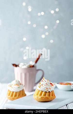 Vanilla muffins with cream cheese cream and caramel sprinkles on a wooden background. Copy space. Stock Photo
