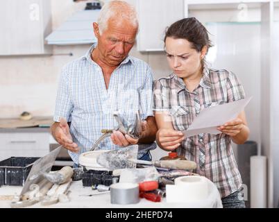 Woman and father discussing instructions for mixer tap Stock Photo