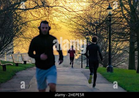 London, UK. 12th January 2022. UK Weather: Early morning joggers run through Primrose Hill park on a chilly but golden sunny morning. Credit: Guy Corbishley/Alamy Live News Stock Photo