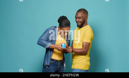 African american man lifting dumbbells and woman helping with weights, standing over isolated background. Couple doing workout exercise with dumbbell to warm up arm muscles and body. Stock Photo