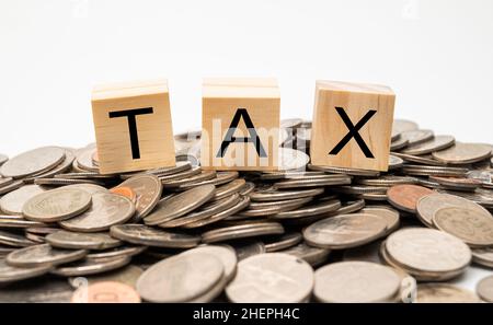 Stacked coins and wooden cube with TAX written on it. Stock Photo