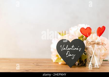 Valentines day festive background with empty black chalkboard heart and 2 lollipop on wooden background. Mockup with copy space for design Stock Photo