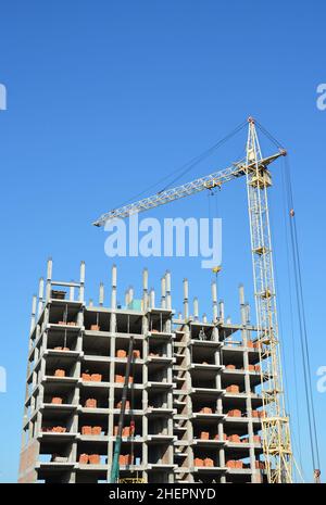 Tower Crane and Building Constructors on Construction Site. Building with two cranes on construction site with builders. Building high rise. Stock Photo