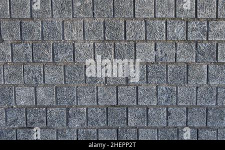 Part of a road made up of square stone tiles. The surface of the masonry is made of granite bricks. Stock Photo