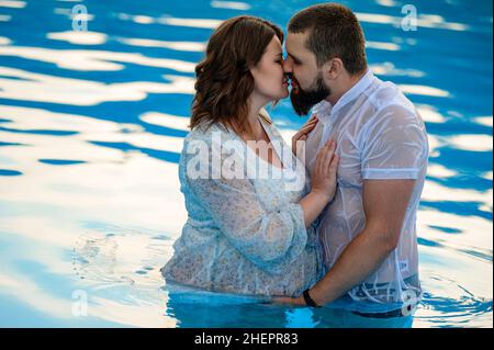 Stryi, Ukraine August 12, 2021: a pregnant woman and her husband swim in the pool, pregnant woman in a dress in the pool. Stock Photo