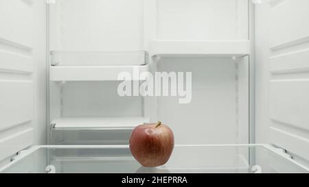 ripe red apple on shelf in empty fridge Stock Photo