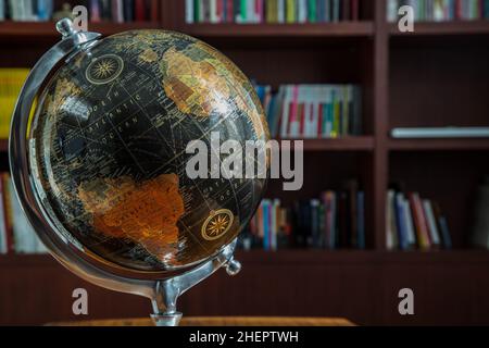 Chiang Rai,Thailand - Sep 06, 2020 : Replica globe on the background of bookshelves in library with copy space. Selective focus. Stock Photo