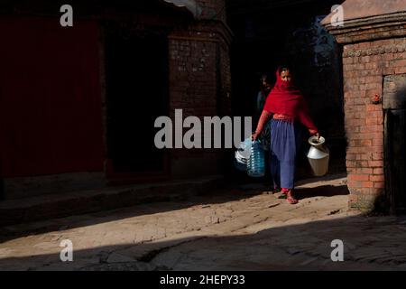 Local Newari woman collecting water in the UNESCO World Heritage city of Bhaktapur, Nepal. Stock Photo