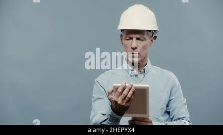 Engineer in hardhat using digital tablet isolated on grey Stock Photo