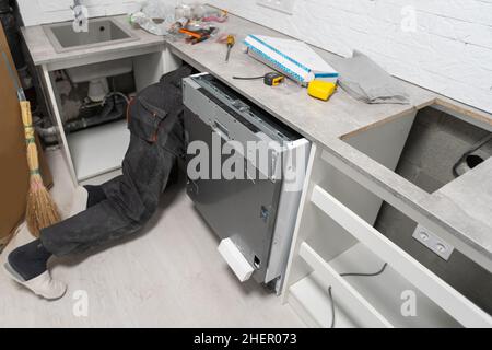 Installation hoses for dishwasher machine domestic connection plumbing pipes in kitchen Stock Photo