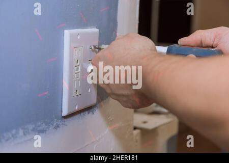 Removing white light switch cover plastic on preparation wall for new paint wall Stock Photo