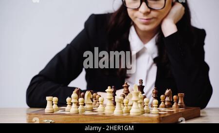 cropped view of businesswoman in glasses playing chess isolated on grey,stock image Stock Photo