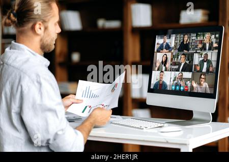Virtual business meeting, online discuss. Side view of a corporate employee communicating with a group of multi-ethnic colleagues via video call, analyzing financial statements, planning strategy Stock Photo