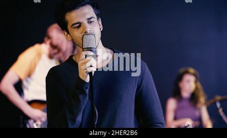 young man singing song with blurred music band,stock image Stock Photo