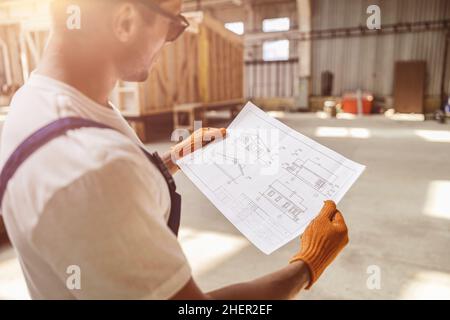 Male worker studying architectural plan at construction site Stock Photo