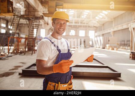 Cheerful male worker holding building architectural plan Stock Photo