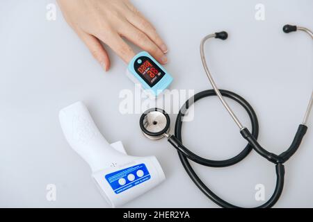Stethoscope, pulse oximeter and thermometer gun on white background. Treatment of cold or flu. Phonendoscope. Infrared isometric thermometer gun to Stock Photo