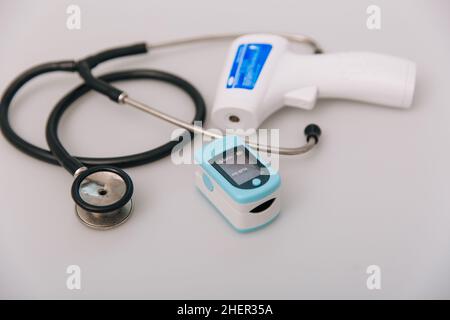 Stethoscope, pulse oximeter and thermometer gun on white background. Treatment of cold or flu. Phonendoscope. Infrared isometric thermometer gun to Stock Photo