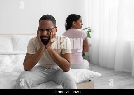 Unhappy offended young african american husband ignores wife, sit on comfortable bed back to back Stock Photo