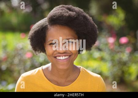 Portrait of happy mid adult woman with afro hairstyle in backyard on sunny day Stock Photo