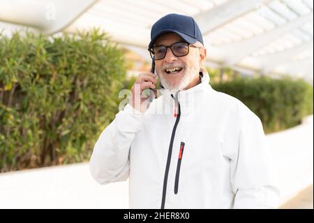 Elderly man talking on smartphone outdoors in the city. Stock Photo