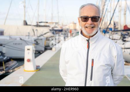 Elderly smiling man spending free time walking on marina. Stock Photo