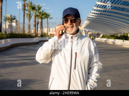 Elderly man talking on smartphone outdoors in the city. Stock Photo