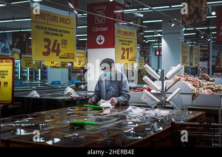 Chisinau, Moldova - October 17, 2021: Inside a supermarket. An elderly man wearing a face shield and protective gloves buys cereals by weight at a Vel Stock Photo