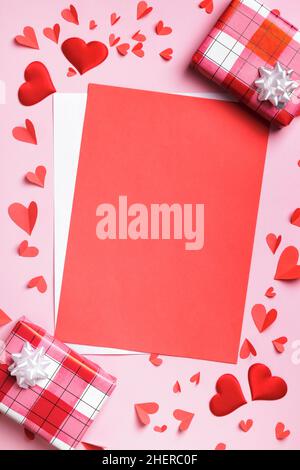 Valentine's day concept with love letter. Blank white sheet of paper hearts boxes with gifts on a pink background. Stock Photo