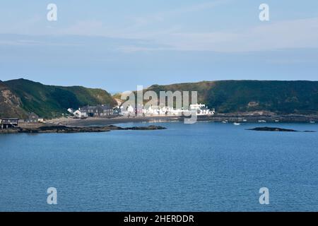 Sunlight picks out the beach village on Porth Dinllaen,North Wales on its rocky peninsula Stock Photo