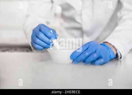 Chemist performs an experiment with liquid nitrogen in laboratory mortar with pestle Stock Photo