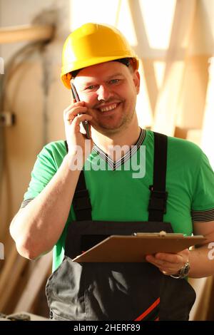 Carpenter in helmet talking on phone and taking order Stock Photo
