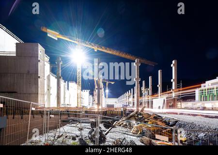 Floodlit tower crane on building construction site at night Stock Photo