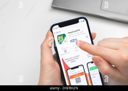 Kharkov, Ukraine - January 10, 2022: PassCovidTG app icon closeup. Woman uses the application on Apple iPhone 12 Stock Photo