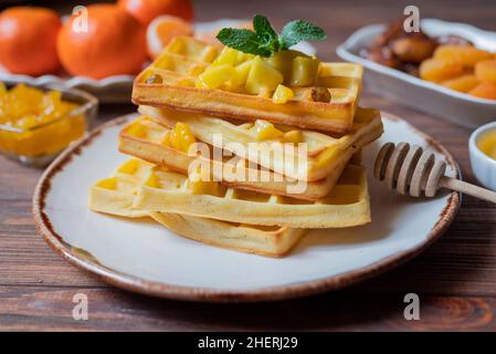 Belgian waffles for breakfast with honey and chunks of mango fruit Stock Photo
