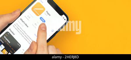 Kharkov, Ukraine - January 10, 2022: Apple Pages app icon closeup, banner design. Woman uses the application on Apple iPhone 12 Stock Photo