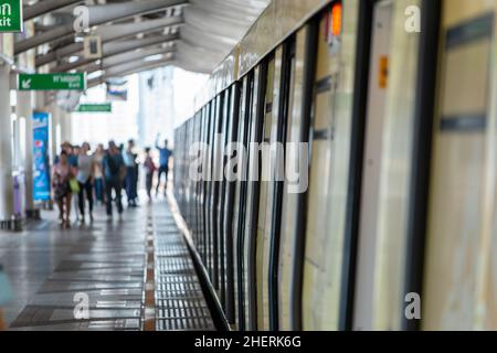 The platform at Saphan Taksin skytrain station in Bangkok. very shallow depth of field with all passengers blurry and out of focus. Small portion of t Stock Photo