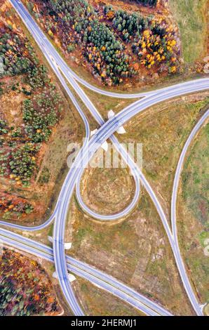 Aerial view on circular road intersection in beautiful autumn forest. Beautiful landscape with empty rural road, trees with red and orange leaves. Hig Stock Photo