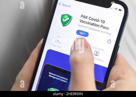 Kharkov, Ukraine - January 10, 2022: PAK COVID-19 Vaccination Pass app icon closeup. Woman with application on Apple iPhone 12 Stock Photo