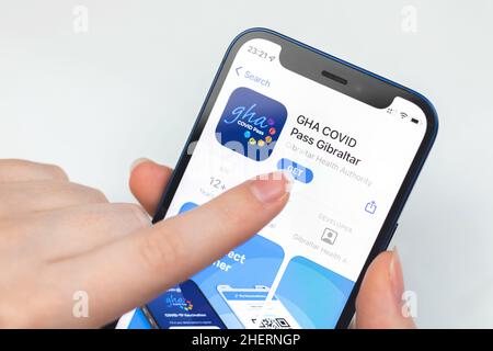 Kharkov, Ukraine - January 10, 2022: GHA COVID Pass Gibraltar app icon closeup. Woman uses the application on Apple iPhone 12 Stock Photo