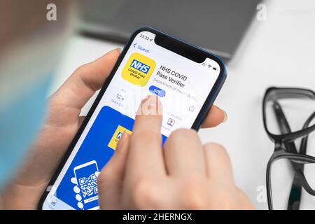 Kharkov, Ukraine - January 10, 2022: NHS COVID Pass Verifier app icon closeup. Woman uses the application on Apple iPhone 12 Stock Photo