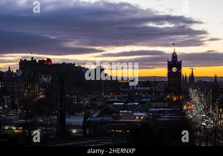 Balmoral clock tower & Princes Street lit up at night with a colourful sunset, Edinburgh, Scotland, UK Stock Photo