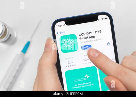 Kharkov, Ukraine - January 10, 2022: COVID-19 DXB Smart app icon closeup. Woman uses the application on Apple iPhone 12 Stock Photo