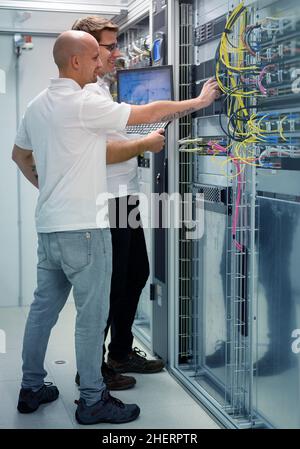 two IT professionals with notebook in server data center room solving a problem Stock Photo
