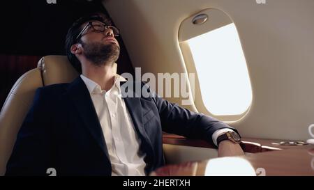 Businessman in formal wear sleeping in private jet Stock Photo