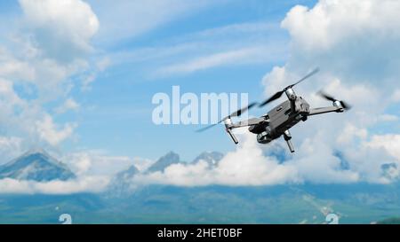 Drone flying overhead in a high cloudy sky with High Tatra mountains on the background Stock Photo