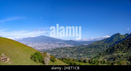 Overlooking the entire city of San Jose Costa Rica and the mountains and volcanoes in the background under blue sky Stock Photo