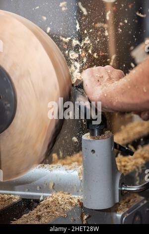 rotating piece of wood and fyling sawdust while making a bowl Stock Photo