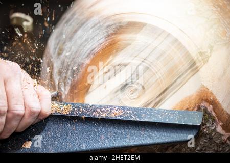 detail macro of wood turning with flying sawdust shavings while making a bowl Stock Photo